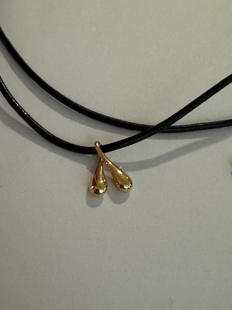 DROOPS Tiny Boobs Gold pendant on a leather strand.