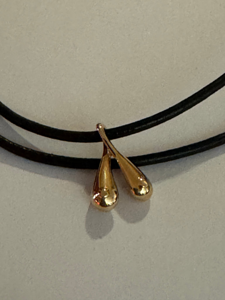 TITTS Tiny Boobs Gold pendant on a leather strand.