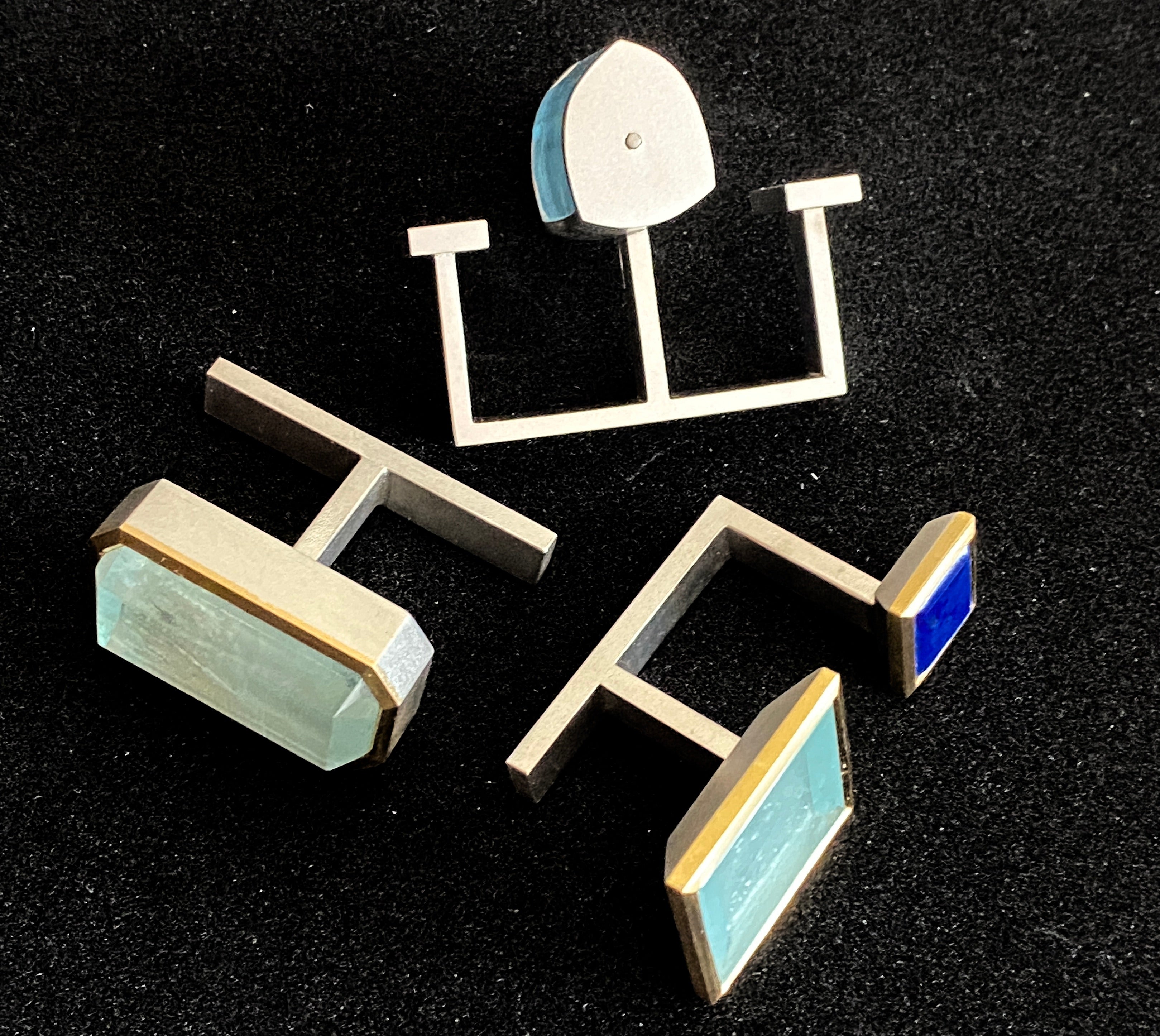 Lamia's Silence is not always golden rings 1 2 & 3 laying in a circle on black background. Made of silver 23k gold lapis and aquamarine 