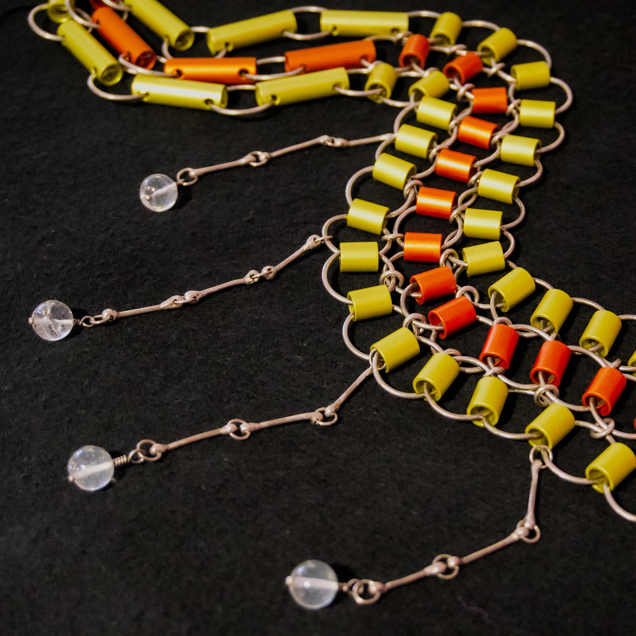 A decorative belt in sterling silver and colored anodised aluminum with rock crystal balls hanging down